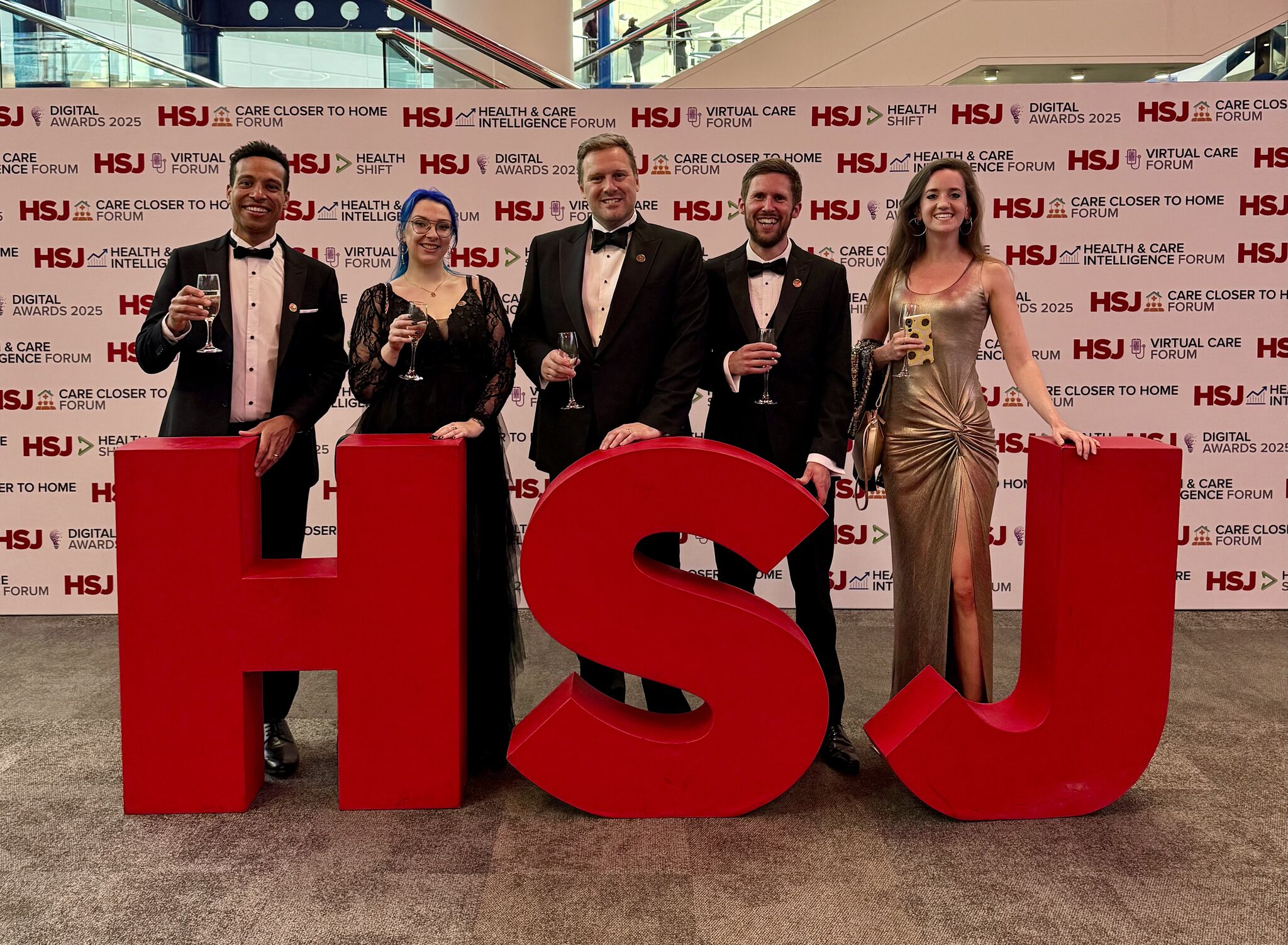 a group standing in front of a HSJ sign holding drinks