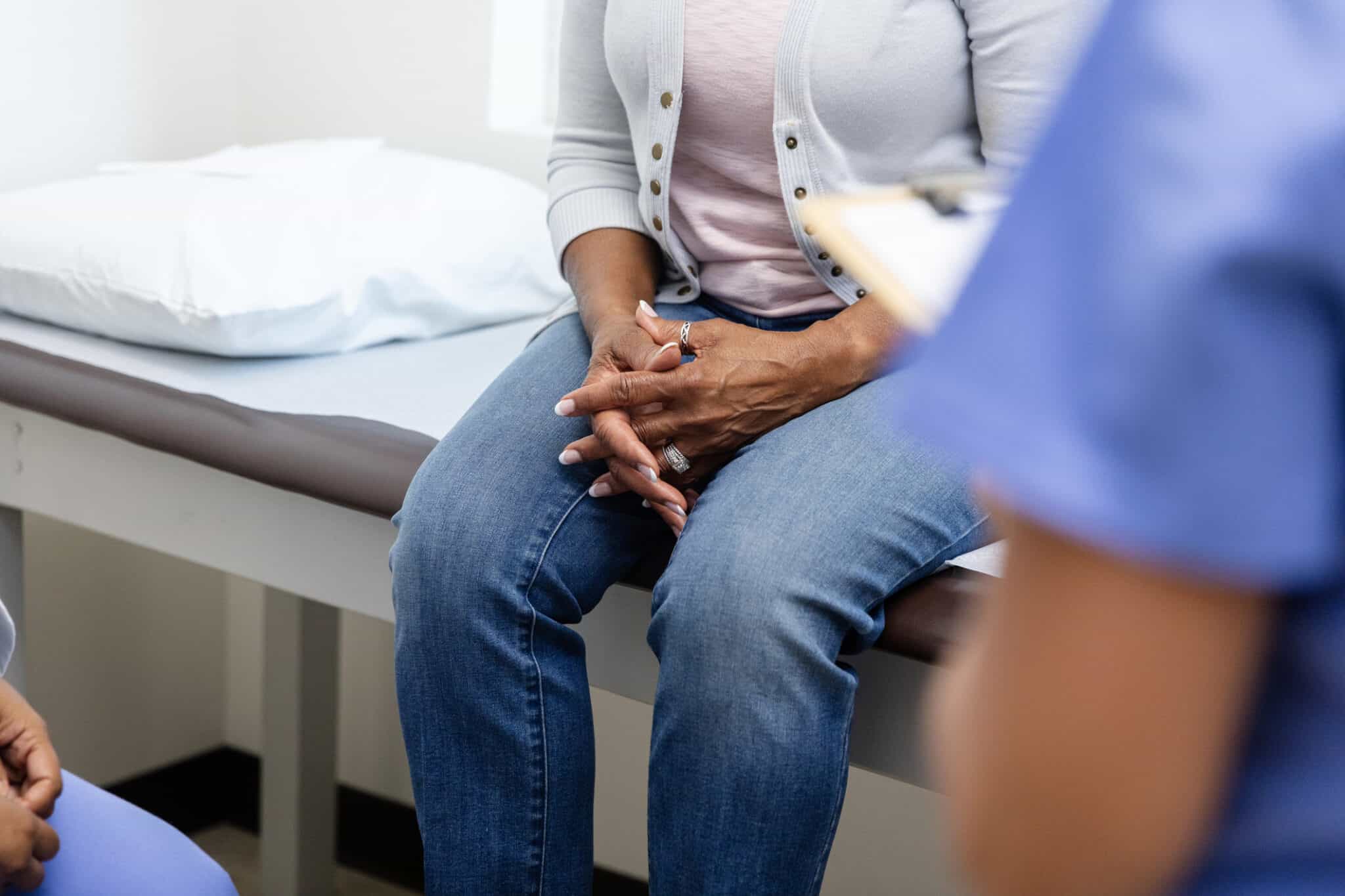 the torso and legs of an individual sat on an examination table